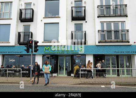 Turisti a Portstewart fuori dalla famosa gelateria Morelli sul lungomare Foto Stock