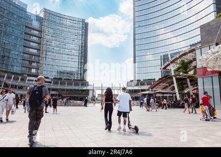 Milano, edifici moderni, persone in sella a scooter elettrico in piazza Gae Aulenti. Italia Foto Stock