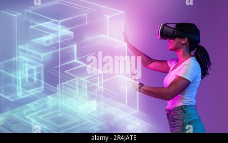 Giovane donna nera positiva in un visore vr che tocca i cubi olografici virtuali luminosi e che utilizza le tecnologie moderne Foto Stock