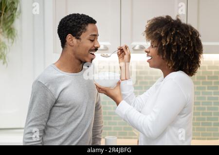 Bella donna nera che alimenta il suo bel marito, fare colazione insieme Foto Stock