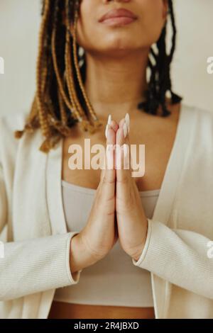 Immagine ritagliata donna afroamericana in piedi, mantenendo le mani in posizione namaste asana. Foto Stock