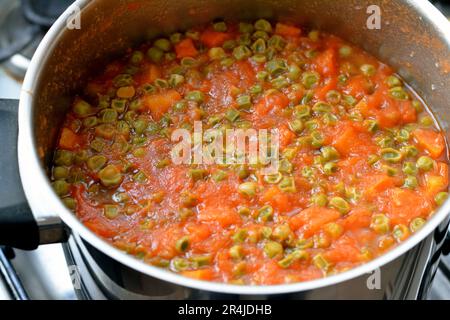 Fette di carote e piselli cotti con salsa di pomodoro, ricchi di vitamine come vitamina A e vitamina C, alcuni minerali di calcio e antiossidanti che si stretolano Foto Stock