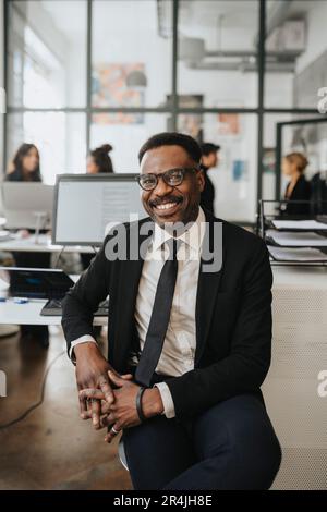 Ritratto di imprenditore maschio felice seduto in ufficio Foto Stock