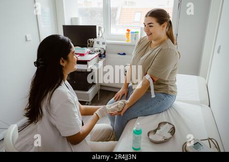 Medico che parla con un paziente sorridente mentre fa un esame medico in clinica Foto Stock