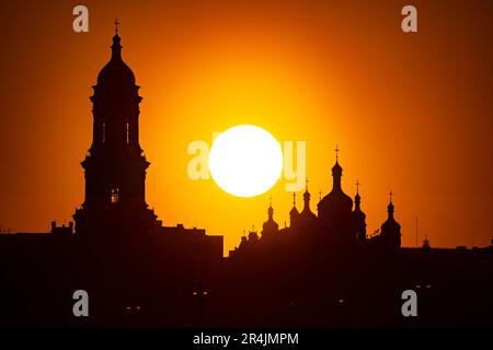 Vista al tramonto della città di Kyiv, Ucraina. Grande tramonto arancione con silhouette a torre del monastero ortodosso di Lavra Foto Stock
