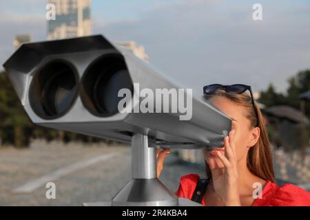 Giovane donna che guarda attraverso la macchina di osservazione turistica alla piattaforma di osservazione Foto Stock