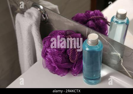 Soffio doccia viola e bottiglia di gel per il lavaggio del corpo sul lavandino in bagno Foto Stock