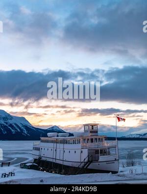 MV Tarahne situato ad Atlin, British Columbia, Canada durante la stagione invernale al tramonto. Foto Stock