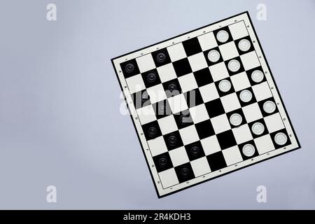 Scacchiera bianca e nera con pedine su sfondo grigio chiaro, vista dall'alto. Spazio per il testo Foto Stock