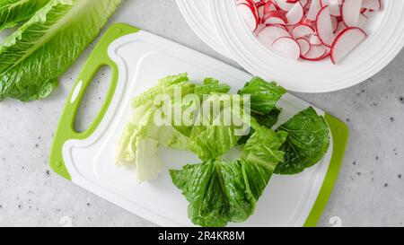 Insalata di primavera ricetta. Mescolando lattuga, spinaci, e ravanello. Primo piano processo di preparazione, ricetta, vista dall'alto Foto Stock