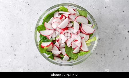 Insalata di lattuga romana con ravanelli freschi affettati primo piano in una ciotola di vetro, vista dall'alto con spazio copia Foto Stock