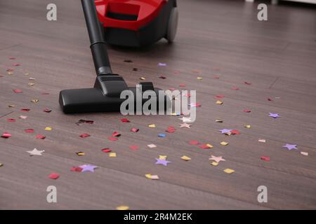 Pulire i confetti dal pavimento in legno in camera Foto Stock