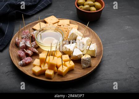 Stuzzichini da dentifricio. Pezzi di formaggio, salsiccia e miele su tavola nera Foto Stock