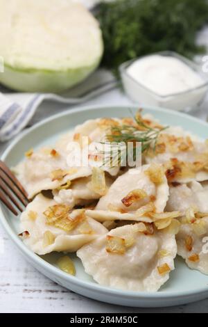 Gnocchi cotti (varenyky) con gustoso ripieno, cipolle fritte e aneto su tavola di legno, primo piano Foto Stock
