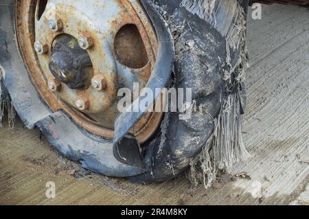 Una grande ruota di gomma nera arrugginita con una lacerazione usurata rotta vecchia piena di pneumatici pneumatico insicuro. Foto Stock