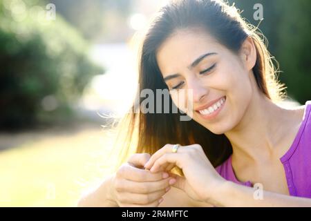 Fidanzato felice guardando l'anello di fidanzamento in un parco Foto Stock