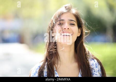 Vista frontale ritratto di una donna felice ridendo con i capelli tousled un giorno ventoso Foto Stock