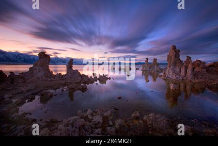 Una lunga esposizione al crepuscolo mostra il movimento delle nuvole che passano sopra le cataste di tufo ultraterreno lungo la riva del famoso Lago Mono della California. Foto Stock