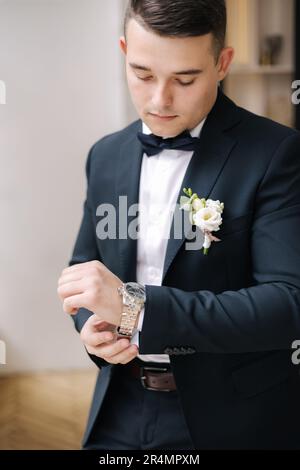 Ritratto di giovane uomo in elegante tuta blu scuro indossa un orologio Foto Stock