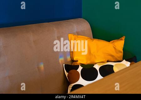 Interno caffè con pareti blu e verde scuro e cuscini arancioni. Design concettuale moderno degli interni a blocchi di colore. Opzione di design interno del ristorante. Foto Stock