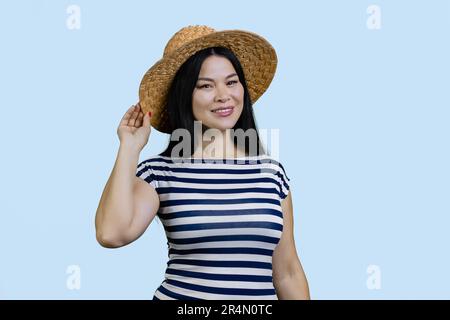 Ritratto di bella giovane donna asiatica che indossa cappello di paglia largo orlo. Isolato su blu pallido. Foto Stock