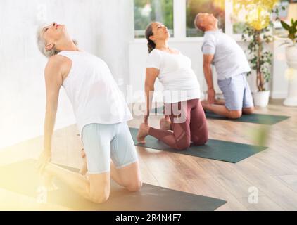 Donna anziana esegue la posa del cammello, Ushtrasana per migliorare la mobilità della colonna vertebrale e stretch muscoli Foto Stock
