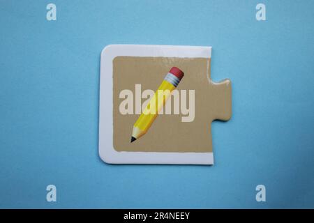 Puzzle di immagine disposti su uno sfondo blu. Matita Foto Stock