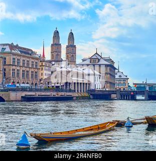 I campanili di Grossmunster e il fiume Limmat con vecchie barche in legno ormeggiati all'argine di Schipfe, Zurigo, Svizzera Foto Stock