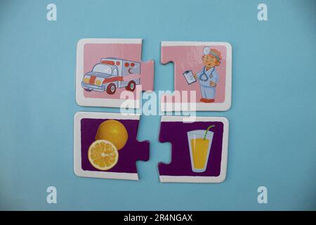 Puzzle di immagine disposti su uno sfondo blu. Arancia tagliata, succo, ambulanza e medico. Foto Stock