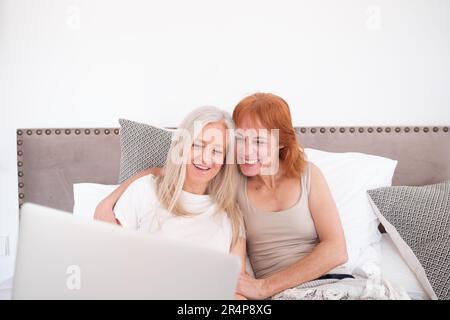 Due donne anziane che guardano una serie insieme prima di dormire sul notebook. Concetto: Stile di vita, condivisione, orgoglio Foto Stock