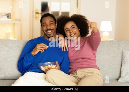 Felice coppia nera con Popcorn guardare film in TV al coperto Foto Stock