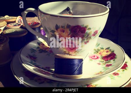 Tazza da tè vintage e piattino con kit da cucito Foto Stock