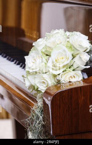 Bouquet di rose bianche che si stenderà sulle chiavi del pianoforte. Decorazioni per feste Foto Stock