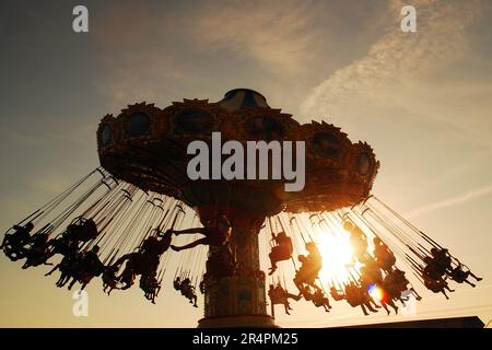 La gente si diverta a fare un giro in altalena al tramonto a Point Pleasant, New Jersey Foto Stock