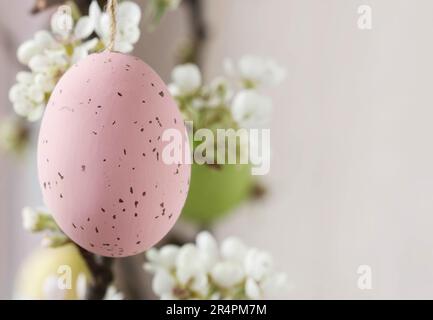 Uova di Pasqua appese sul ramo fiorente dell'albero di mela. Arredamento festivo Foto Stock