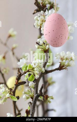 Uova di Pasqua appese sul ramo fiorente dell'albero di mela. Arredamento festivo Foto Stock