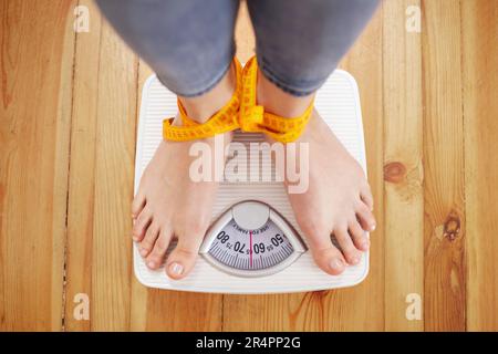 Piedi femmina su scale bianche legati con metro a nastro. Foto Stock