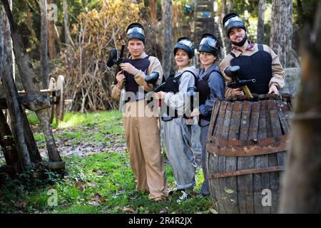 Amici che posano sul campo di paintball Foto Stock