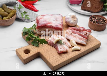 Gustoso ingrasso di maiale con aglio ed erbe su tavola di marmo bianco Foto Stock