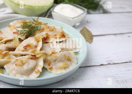 Gnocchi cotti (varenyky) con gustoso ripieno, cipolle fritte e aneto su tavola di legno, primo piano Foto Stock
