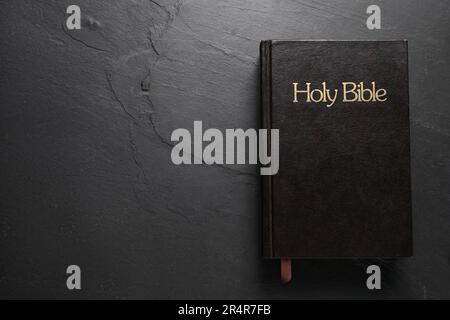Hardcover Bibbia su tavola nera, vista dall'alto con spazio per il testo. Libro religioso Foto Stock