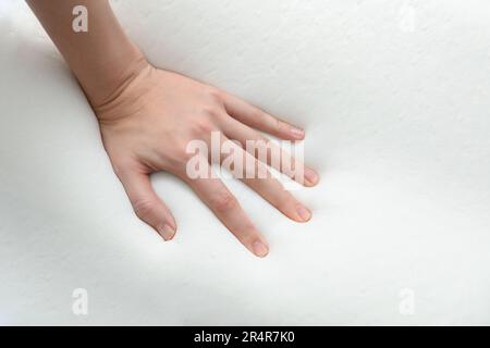 Donna toccante ortopedico cuscino in schiuma memoria su sfondo bianco, primo piano Foto Stock