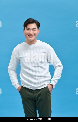Elegante e attraente giovane uomo sorridente che indossa una t-shirt bianca in posa in studio Foto Stock