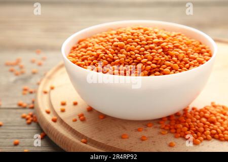 Lenticchie rosse in ciotola bianca su un tavolo di legno grigio. Vista dall'alto. Foto Stock