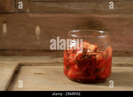 Cavolo di nappa di kimchi in vaso su un tavolo di legno rustico, verdure fermentate tradizionali coreane con pasta di Gochujang. Copia spazio per testo. Foto Stock