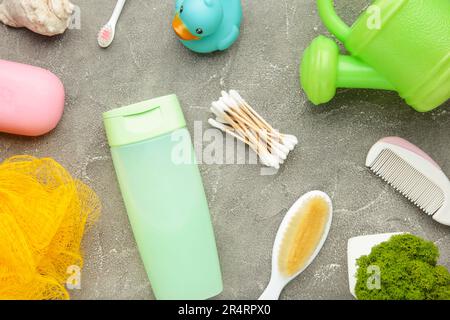 Roba piatto del bambino della foto del lay. Spugna, sapone, gel doccia, anatra di gomma, pettine su grigio. Foto Stock