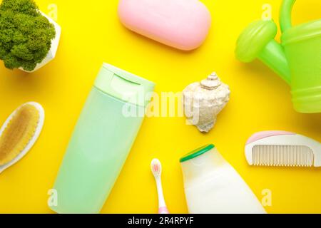 Roba piatto del bambino della foto del lay. Spugna, sapone, gel doccia, anatra di gomma, pettine sul giallo. Foto Stock