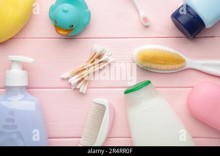 Roba piatto del bambino della foto del lay. Spugna, sapone, gel doccia, anatra di gomma, pettine su rosa. Foto Stock