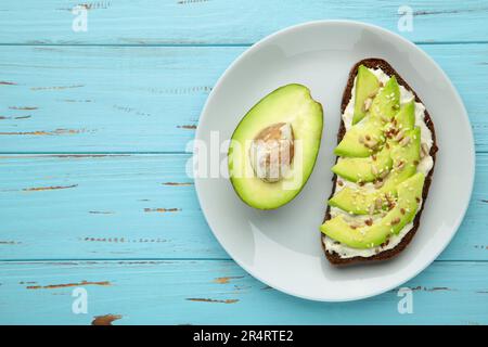 Panino di avocado su pane di segale scuro, composto da metà di avocado su sfondo blu. Vista dall'alto Foto Stock