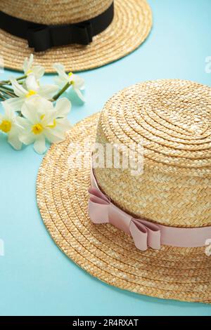 Cappelli di paglia con fiori primaverili su sfondo menta. Vista dall'alto Foto Stock